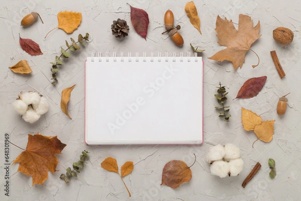 Fototapeta Autumn leaves with notebook on concrete background, top view
