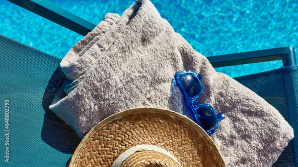 Fototapeta 16:9 still life relaxation concept on vacation. Hammock next to the pool with summer accessories. Towel, sunglasses and straw hat.
