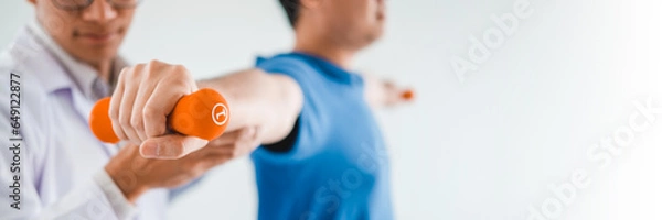 Obraz Physiotherapist man giving exercise with dumbbell treatment About Arm and Shoulder of athlete male patient Physical therapy concept