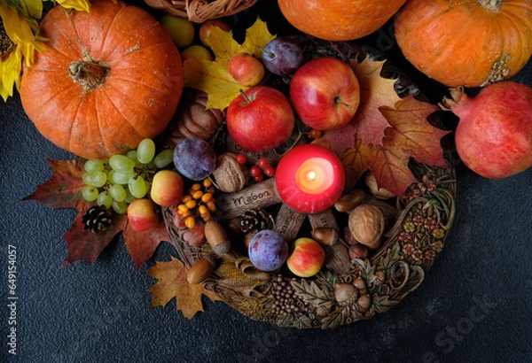Fototapeta Wiccan altar for Mabon sabbat. fruits, pumpkins, candle, nuts and wheel of the year on abstract dark background. Witchcraft, esoteric spiritual ritual for fall season. symbol of Harvest. top view