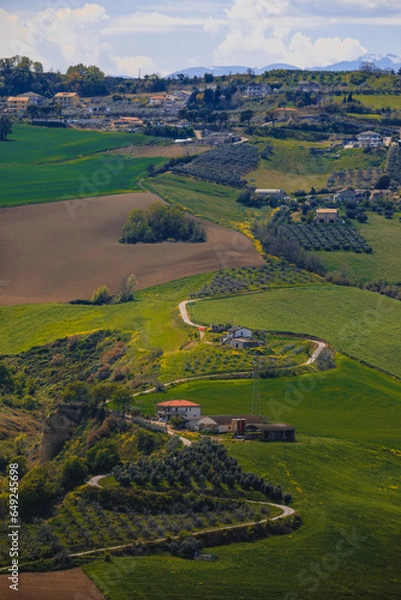 Fototapeta A winding road in the picturesque hills of the Ambruzzo region of Italy, the photo was taken in the rays of the setting sun. view of the village of Montagnola.