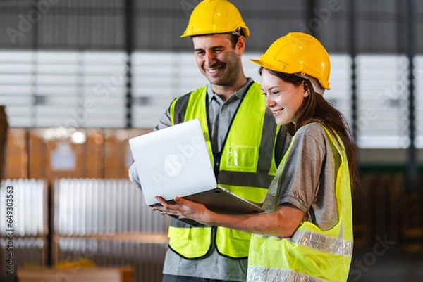Fototapeta Warehouse worker logistic team wearing hard hat working in aisle between tall racks with packed goods warehouse for industry business of import, export delivery to global market, shipping management