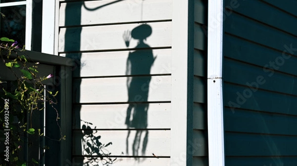 Fototapeta A black shadow displaying eerie dolls hanging is presented on a white wall for Halloween