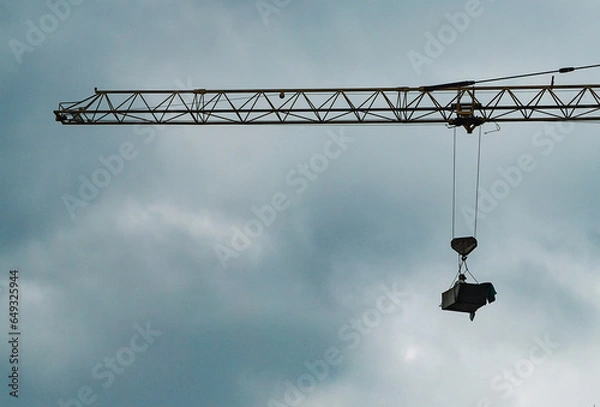 Fototapeta A construction worker suspended from a construction crane arm