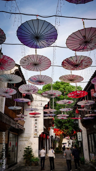 Fototapeta In a small town in Hangzhou, China, colorful umbrellas line the streets