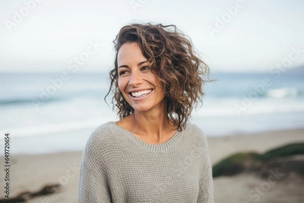 Fototapeta Portrait of a Israeli woman in her 40s wearing a cozy sweater against a beach background