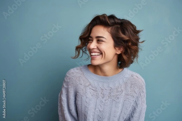 Fototapeta portrait of a happy Mexican woman in her 30s wearing a cozy sweater against an abstract background