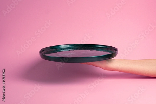 Obraz Empty green plate held in hand. Pink background.