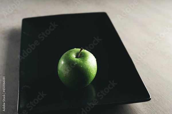 Obraz fresh green apple on black elongated plate