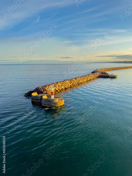 Obraz Small lighthouse at the end of a harbor pier