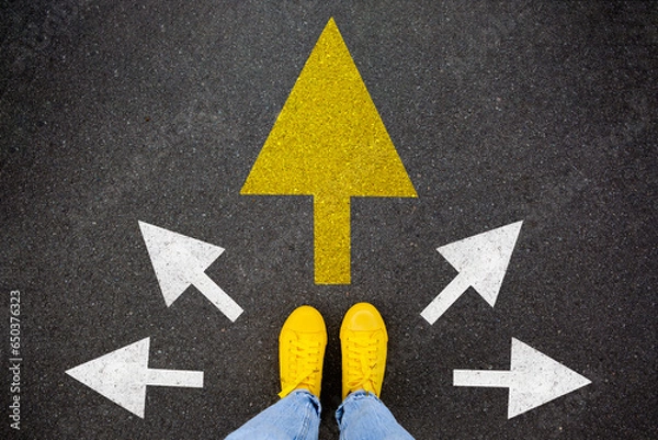 Fototapeta Feet walking away with directions arrow. Taking main decision for the future. Sneaker shoes top view road. Hipster woman standing on floor or pathway to success. Creative idea, future concept