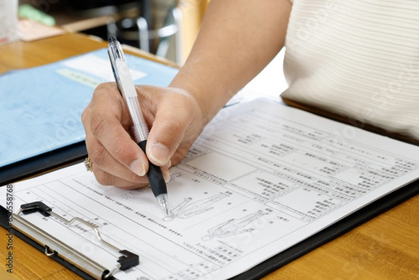 Obraz 記入する女性の手元。申し込み、契約、問診