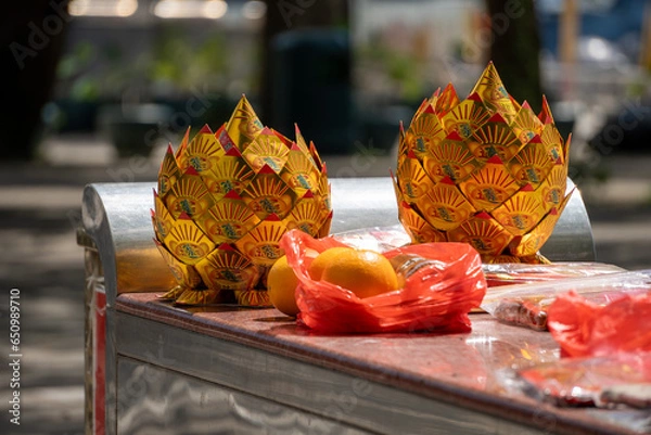 Obraz Folded paper flower balls used for rituals, with "Attract Wealth and Prosperity" written on them, and some fruits.