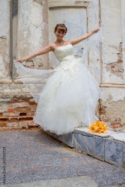 Obraz Невеста идет по бордюру, букет желтых лилий у старой церкви