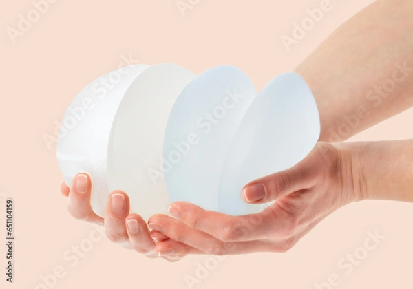 Obraz  Female hands holding stack of different types of breast implants.