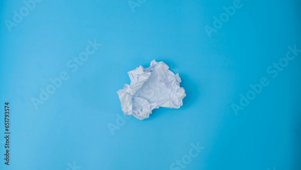 Fototapeta A paper ball is spread out into a blank sheet on blue background. Crumpled blank white paper with copy space for text or advertising space.