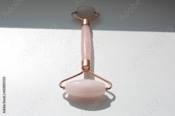 Obraz Pink face roller on white background with shades.