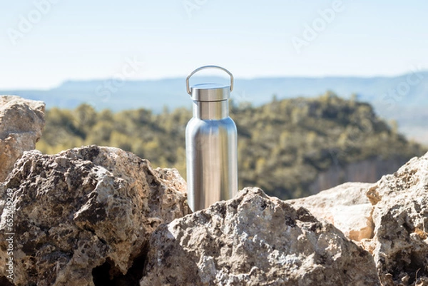 Obraz Thermal bottle on a rock on top of a mountain