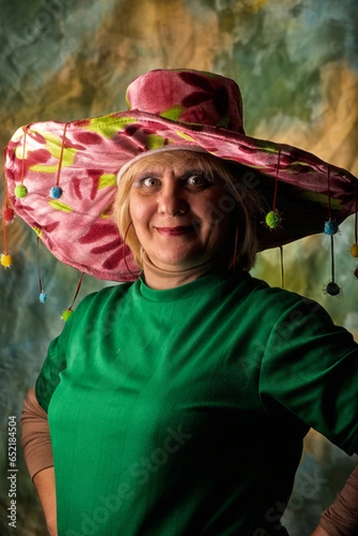 Obraz Clown in a hat. The buffoon grimaces and entertains. Portrait of a dressed up artist.