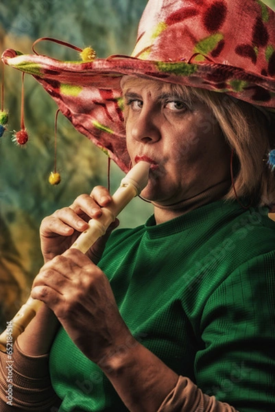 Obraz Clown in a hat. The buffoon grimaces and entertains. Portrait of a dressed up artist.