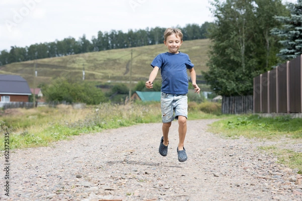 Fototapeta happy boy running through the streets of the village, vacation
