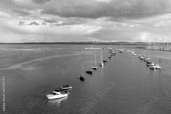 Fototapeta Looking out over the harbour with boats in black and white