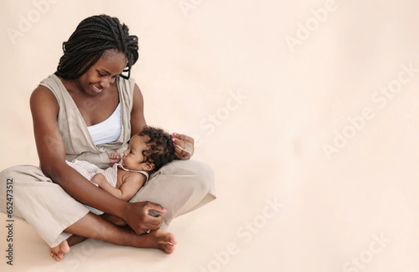 Fototapeta African-American mother with baby on beige background Minimalist portraits, space for text