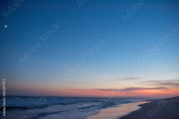 Obraz tufts of clouds engulf the sunset with the mooon overlooking the ocean