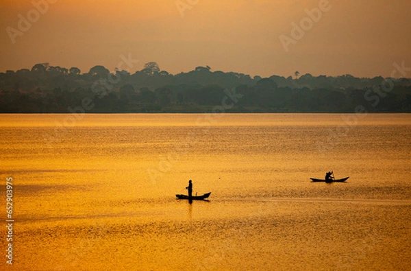 Fototapeta fishermen cast nets from their boats on Lake Victoria at sunrise in Uganda