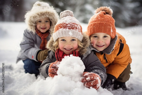 Fototapeta The children build a snowman in the backyard of the house.
