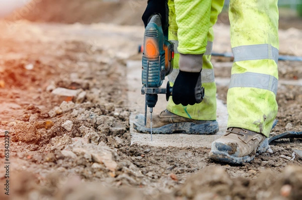 Fototapeta Builder drilling through hard concrete with a cordless drill