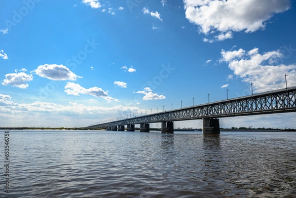Fototapeta A motorway and railway bridge across the river. Blue calm river water and blue cloudy sky