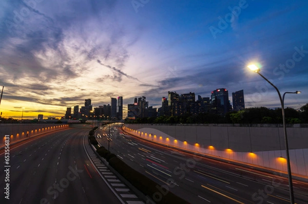 Fototapeta express highway leads to singapore city down town city central district in sunset time, highway bridge with many skyscraper financial buildings in background during rush hour