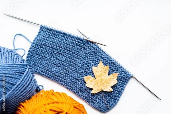 Obraz A piece of cloth knitted with blue threads and two balls of blue and yellow threads on a white background 