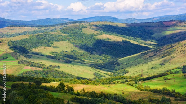 Fototapeta rural landscape of carpathian mountains. beautiful countryside scenery in autumn season with fields on the hills in the valley