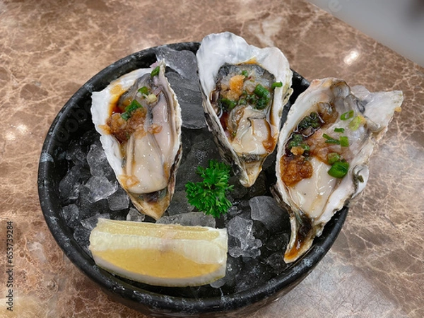 Fototapeta Fresh oysters with red with soy sauce served on ice.