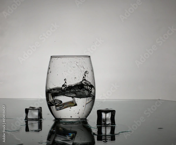Obraz splash on a glass of water with ice cubes.