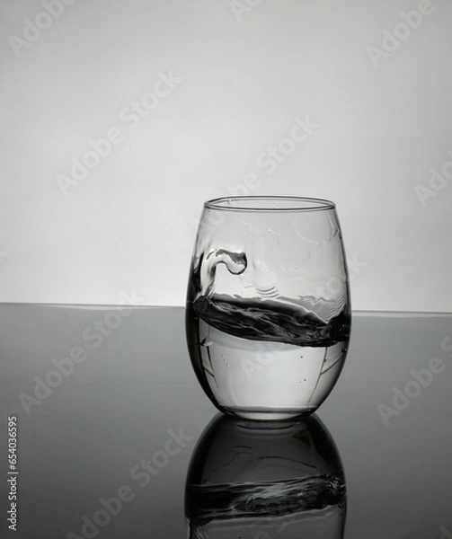 Obraz small glass of water on white background with a little splash.