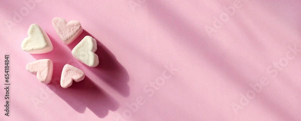 Fototapeta Delicate pink and white marshmallows in the shape of a heart on a pink background with copy space, closeup. Valentine's Day symbols tender marshmallow sweets heart shape on banner.