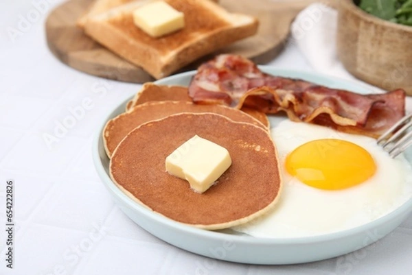 Fototapeta Tasty pancakes served with fried egg and bacon on white tiled table, closeup
