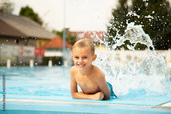 Obraz A seven-year-old boy of European appearance poses and makes faces near the pool.