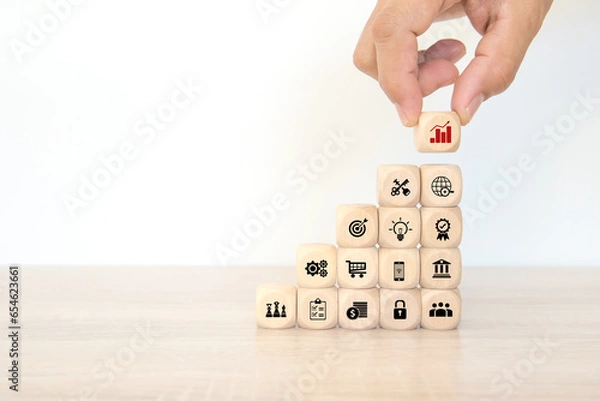 Fototapeta Hand choose cube wooden block stack pyramid with graph and business strategy icon for target goal to growth and financial marketing analysis or human resource management and investment concepts.