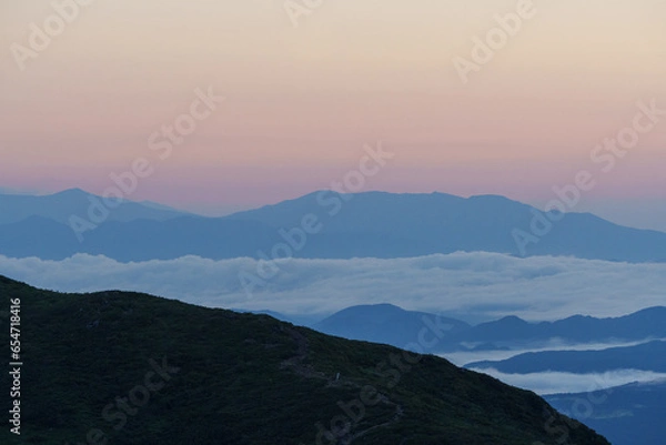 Fototapeta 夜明け前の暗い山々の稜線と雲海と朝日に照らされて赤くなる空　栃木県那須