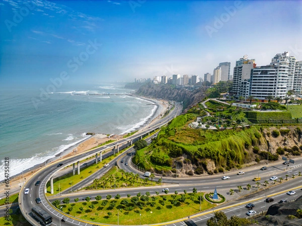 Fototapeta Aerial image of Mirador Arturo Polanco with luxury houses on the stone hillside, large avenue Bajada de Armendariz and Playa La Estrella in the background.
