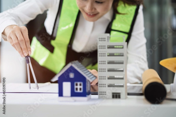 Fototapeta Female architect hands making model house. woman architect working in the office.