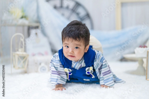 Fototapeta バースデーフォトセットで1歳の誕生日に一生餅を背負ってハイハイするつらそうな表情の赤ちゃん