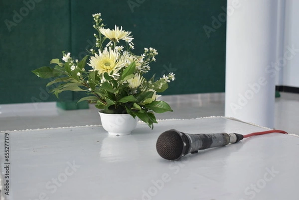 Fototapeta photo of a flower vase and microphone on a white table