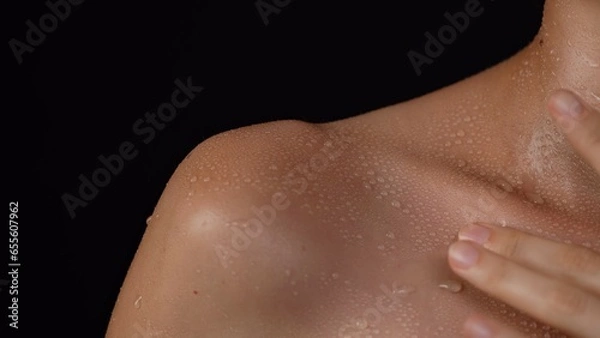 Fototapeta Closeup shot of caucasian woman body part in studio light, shoulder and collarbone area touching skin in water drops after bathing.