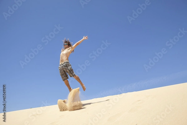 Fototapeta young man jumping happy in the desert