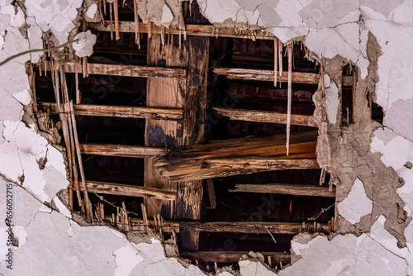 Fototapeta A massive hole in the ceiling revealing old, charred beams in an ancient house. Evokes the passage of time and the transience of aging materials